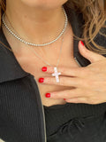 Pink gem cross pendant held between fingers while worn