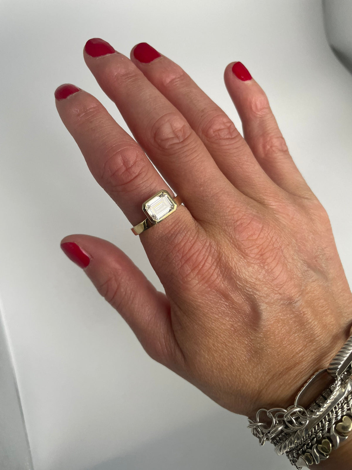 Gold-tone emerald-cut ring on the hand, alternate angle