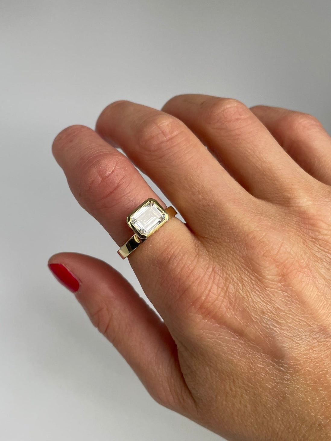 Gold-tone emerald cut ring worn on the hand, top view