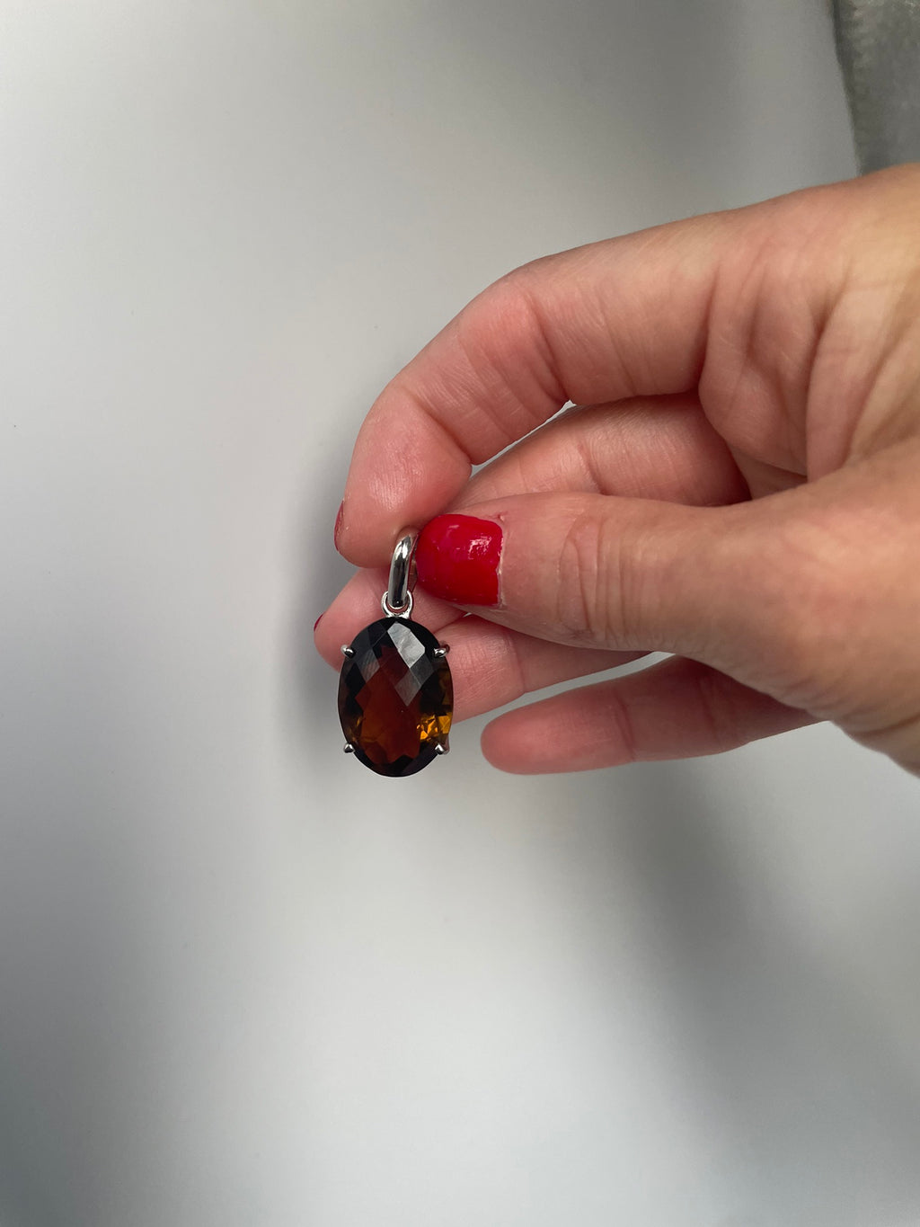 Smoky quartz pendant hanging from its bail, in hand