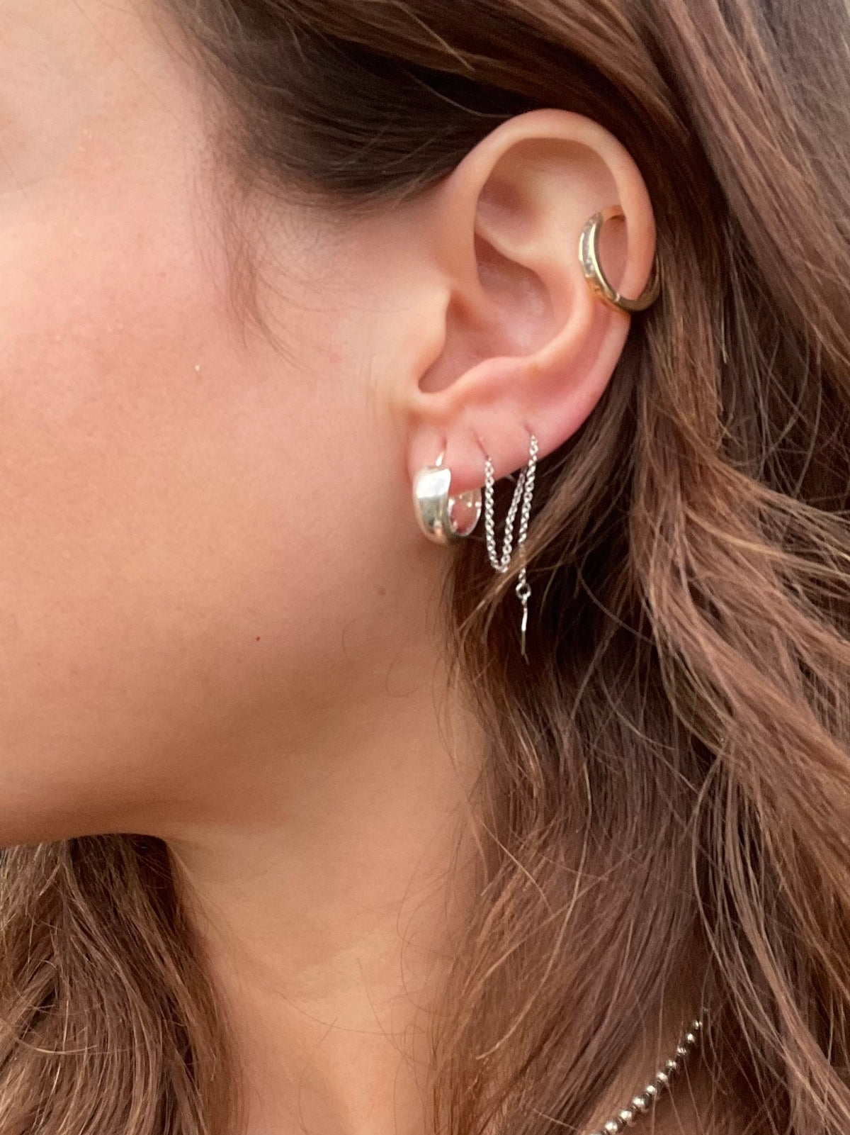 Silver huggie hoop on the ear, side view