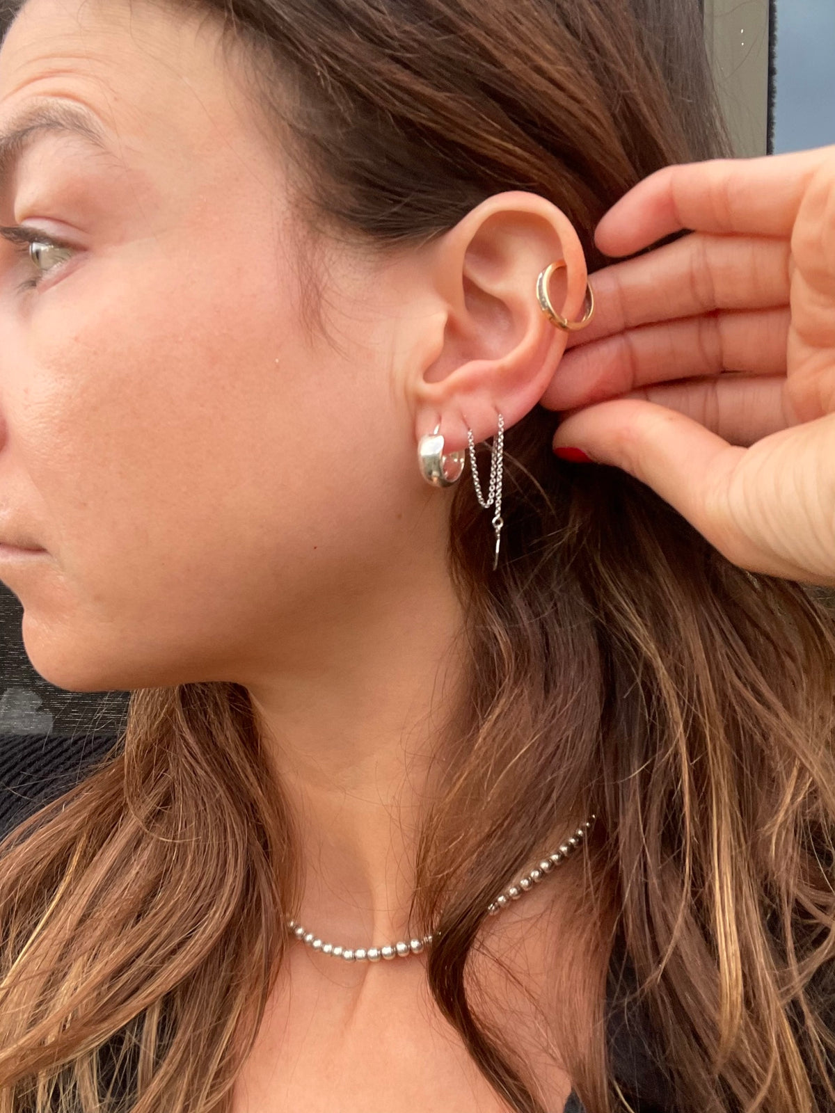 Silver huggie hoops styled in an ear stack, wider view