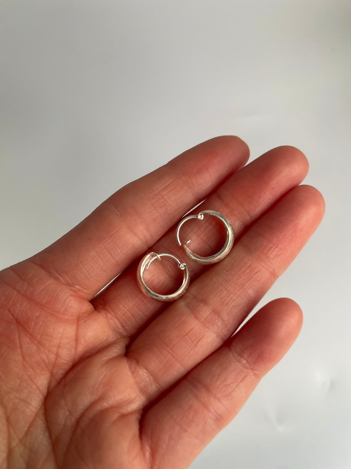 Pair of sterling silver huggie hoops in the palm