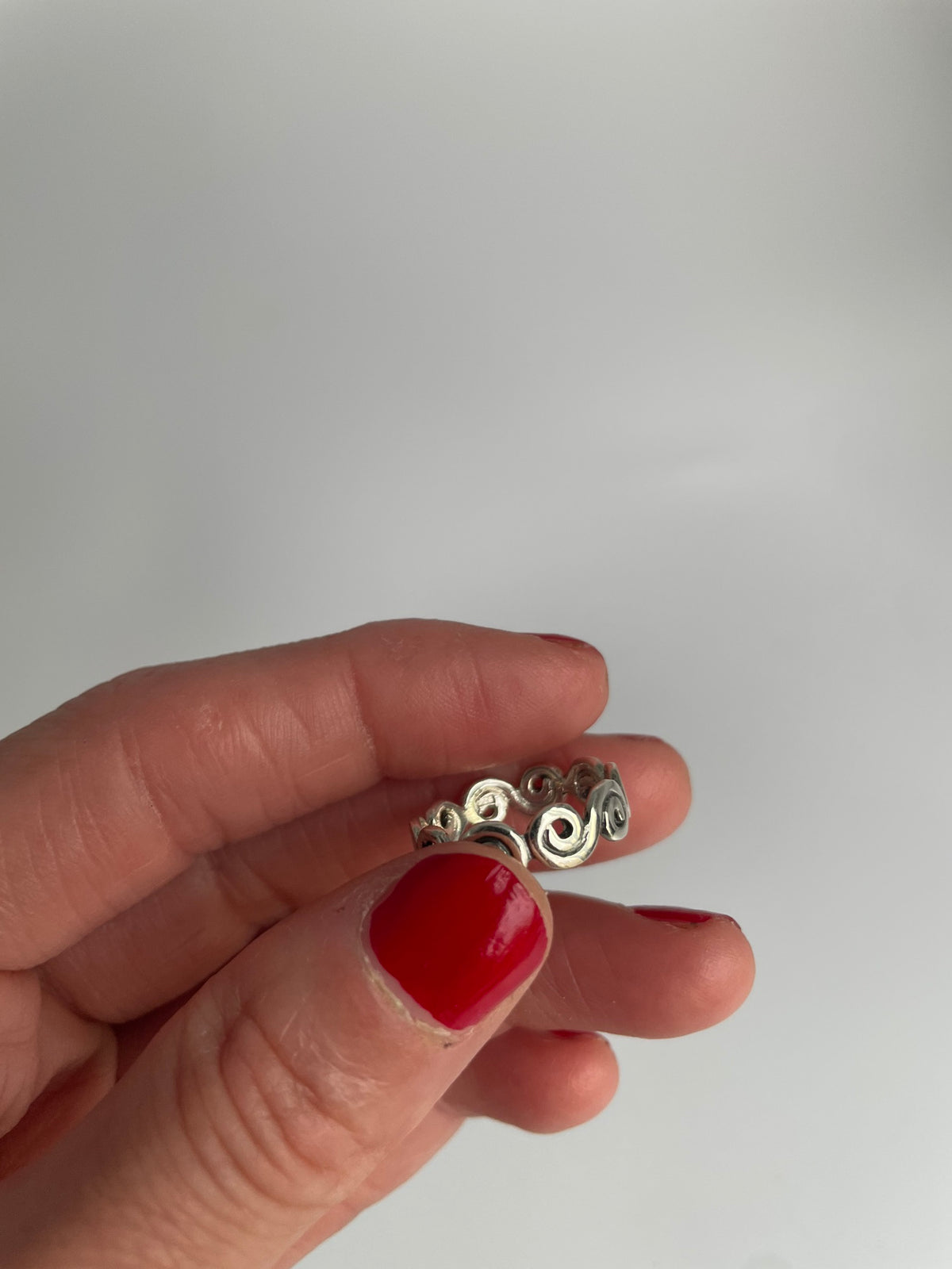 Openwork swirl ring resting on fingertips