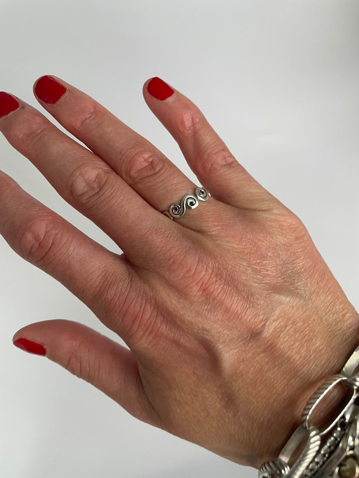 Swirl ring worn on the hand, styled with bracelets