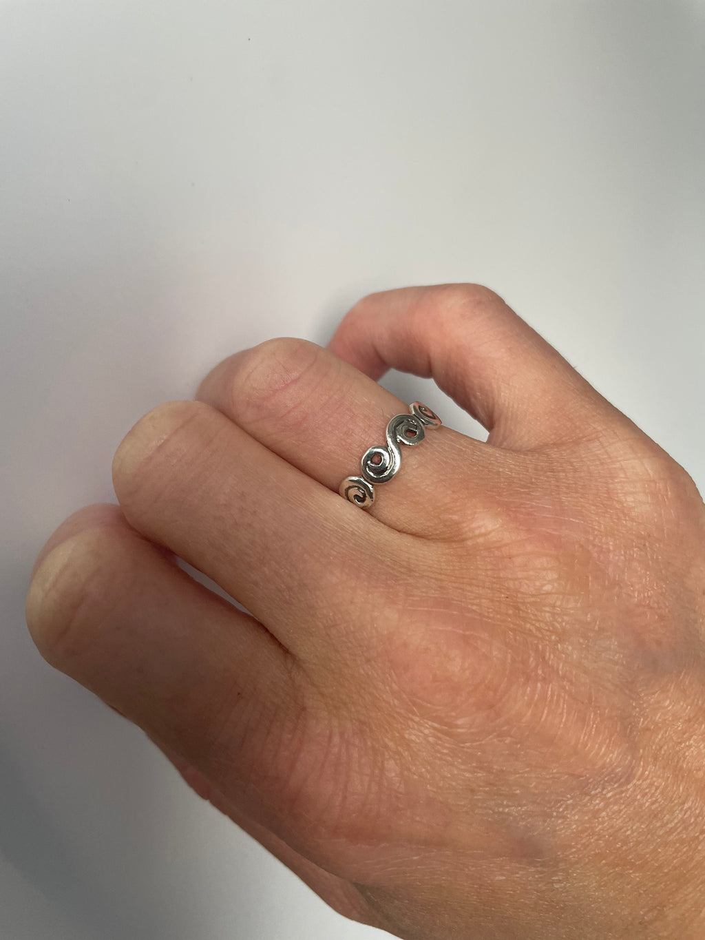 Silver swirl band ring worn on the finger, close view