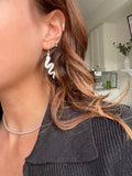 Silver snake earring worn on the ear, styled with a beaded choker and ear studs