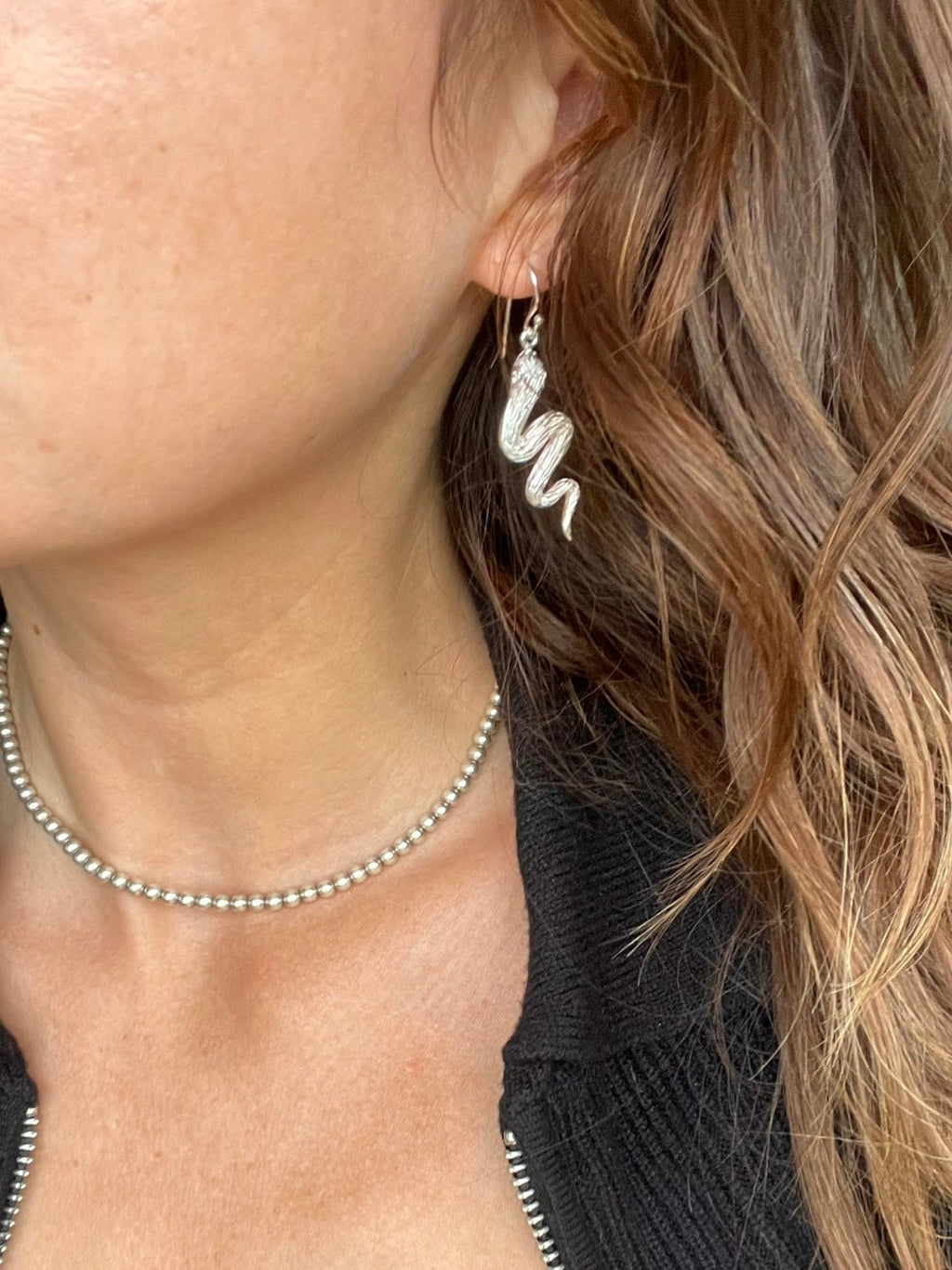 Snake dangle earring worn with a beaded choker, side view