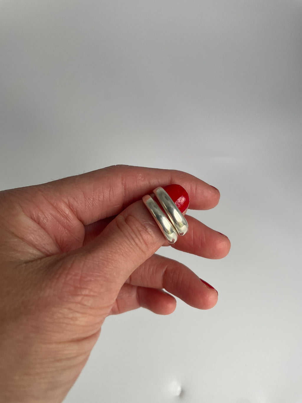 Polished silver double band ring with two domed bands joined at the back, held in fingers
