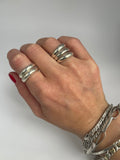 Double band silver ring worn on the hand alongside a triple band ring, with bracelets for styling