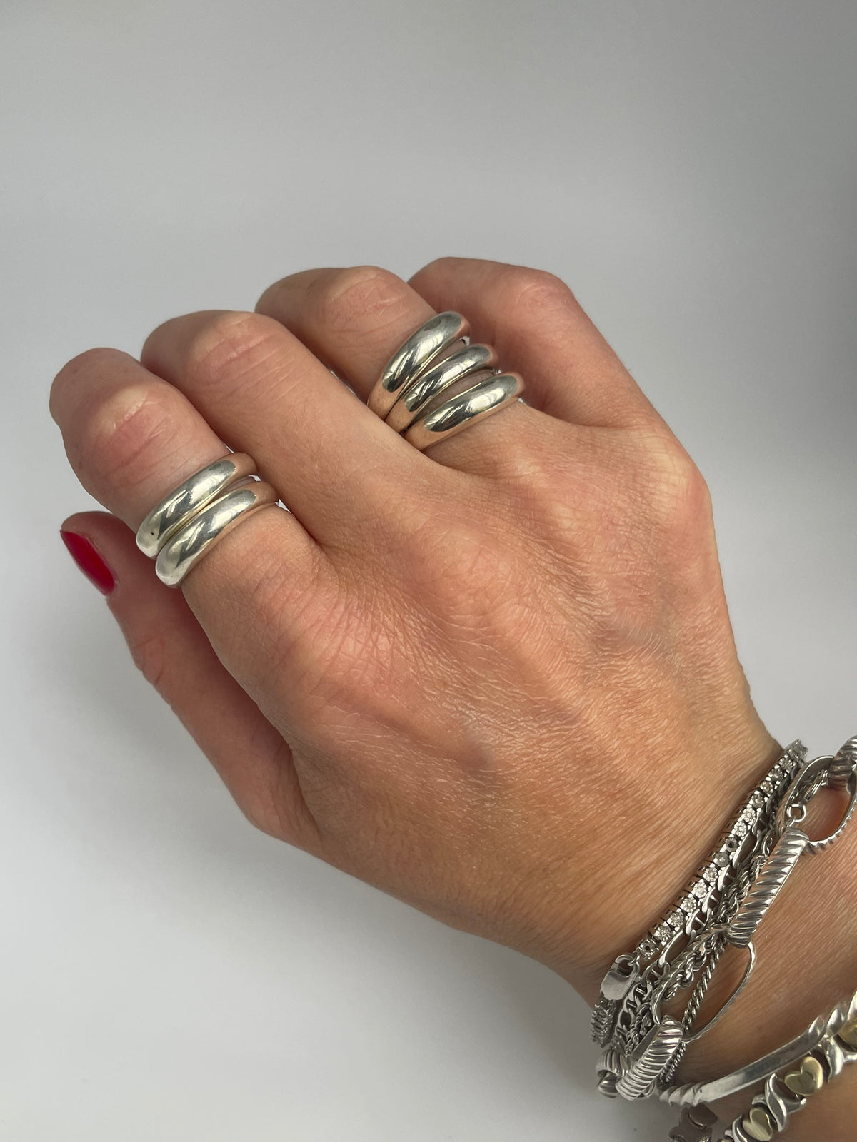 Double band silver ring worn on the hand alongside a triple band ring, with bracelets for styling