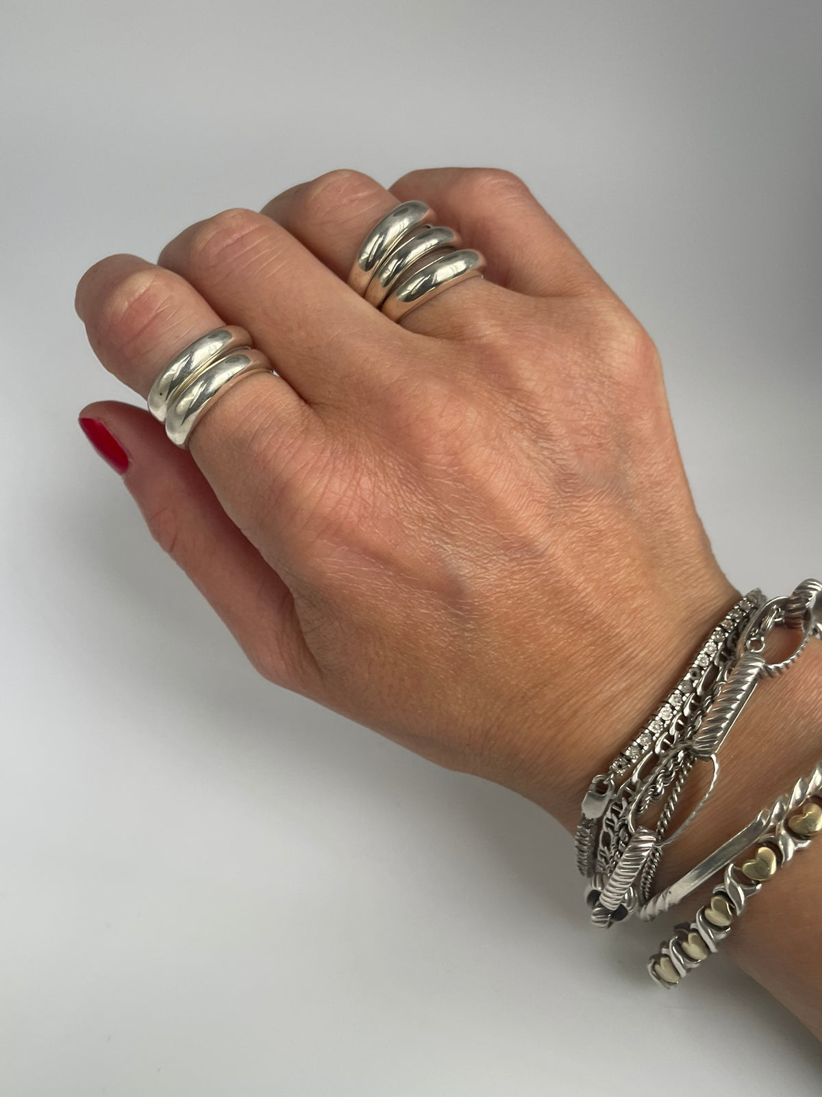 Polished double band ring on the index finger, styled with a triple band ring and bracelets