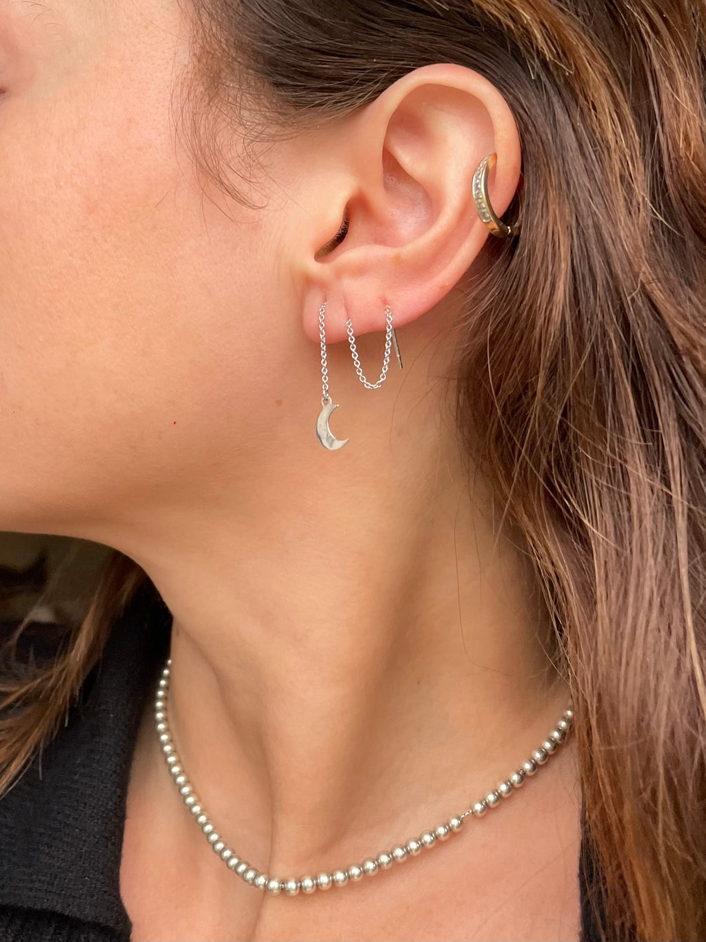 Crescent moon threader earring worn with the chain looped through a second piercing