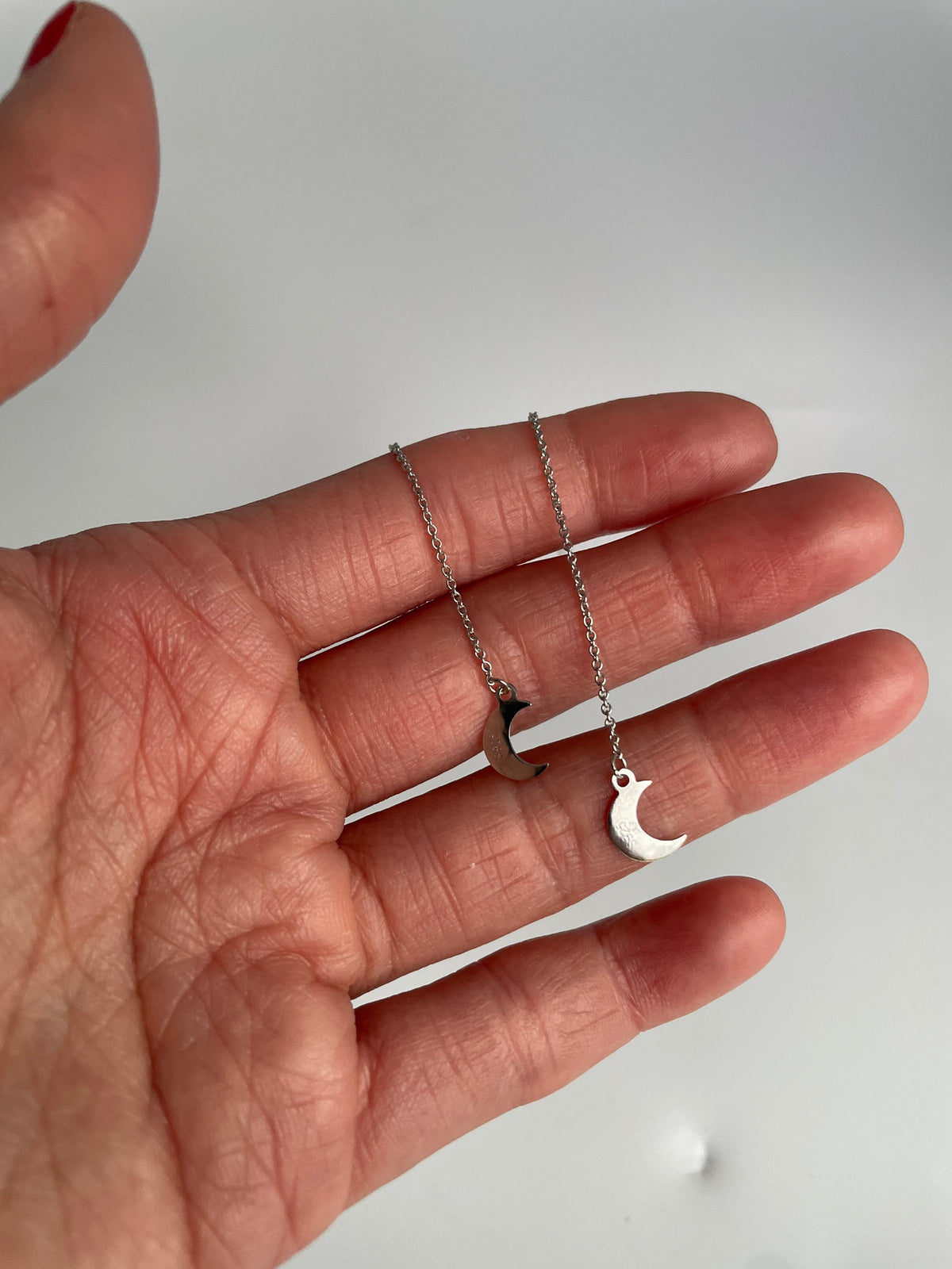 Crescent moon threader earrings hanging over fingers
