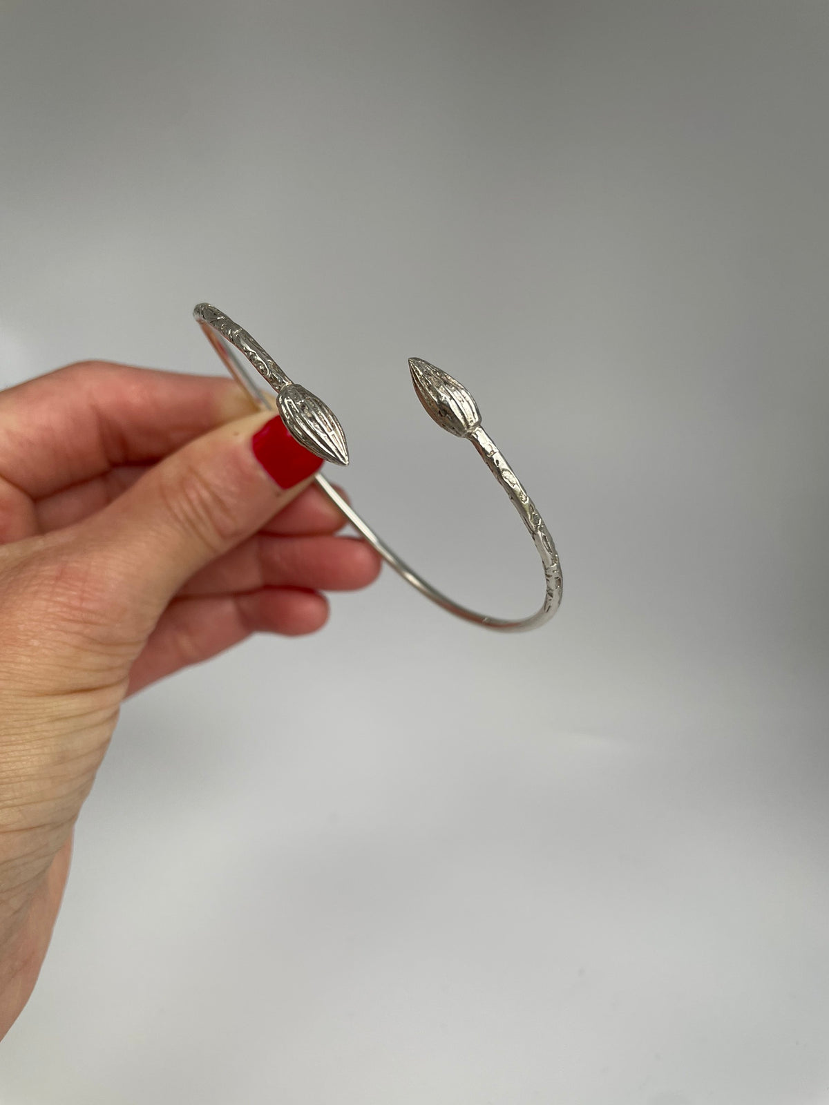 Vintage silver open cuff bracelet with ribbed cocoa pod ends, held in hand