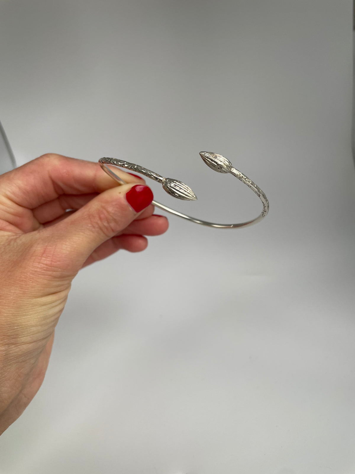 Silver cuff bracelet with engraved band ends and pointed pod terminals