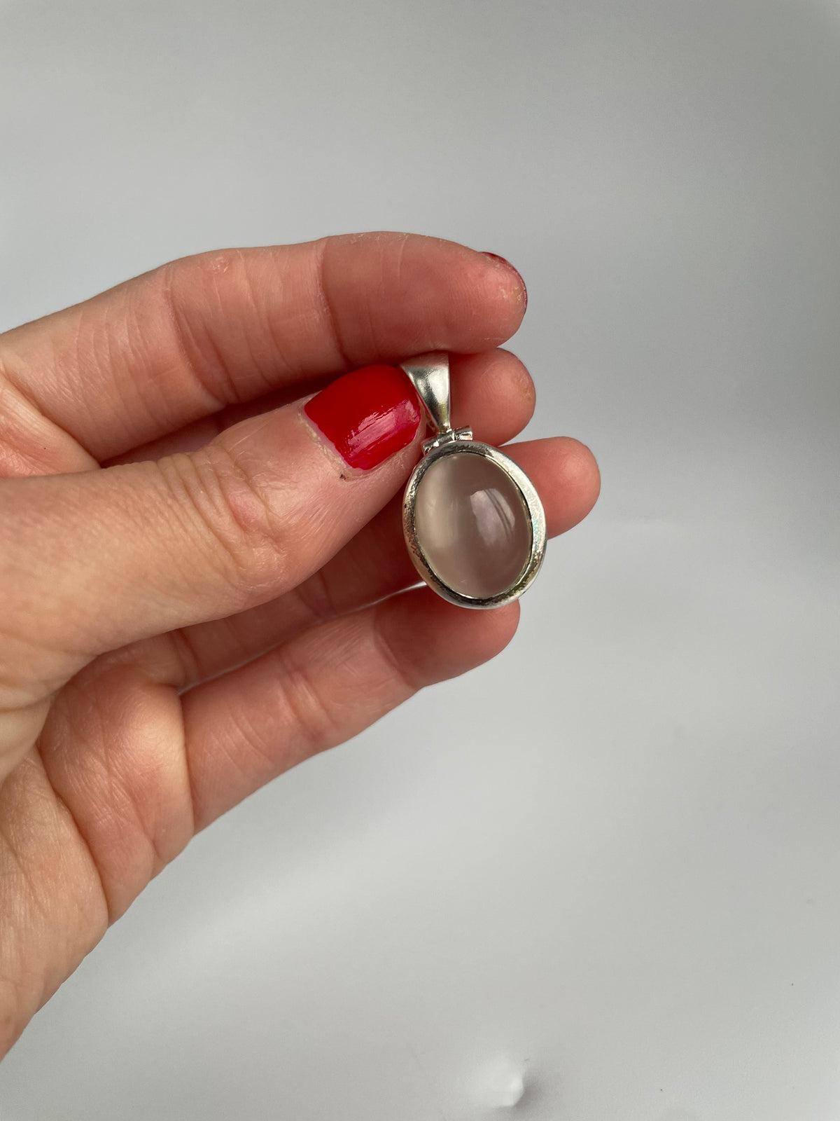 Close view of the oval cat's eye cabochon in a polished silver bezel with tapered bail