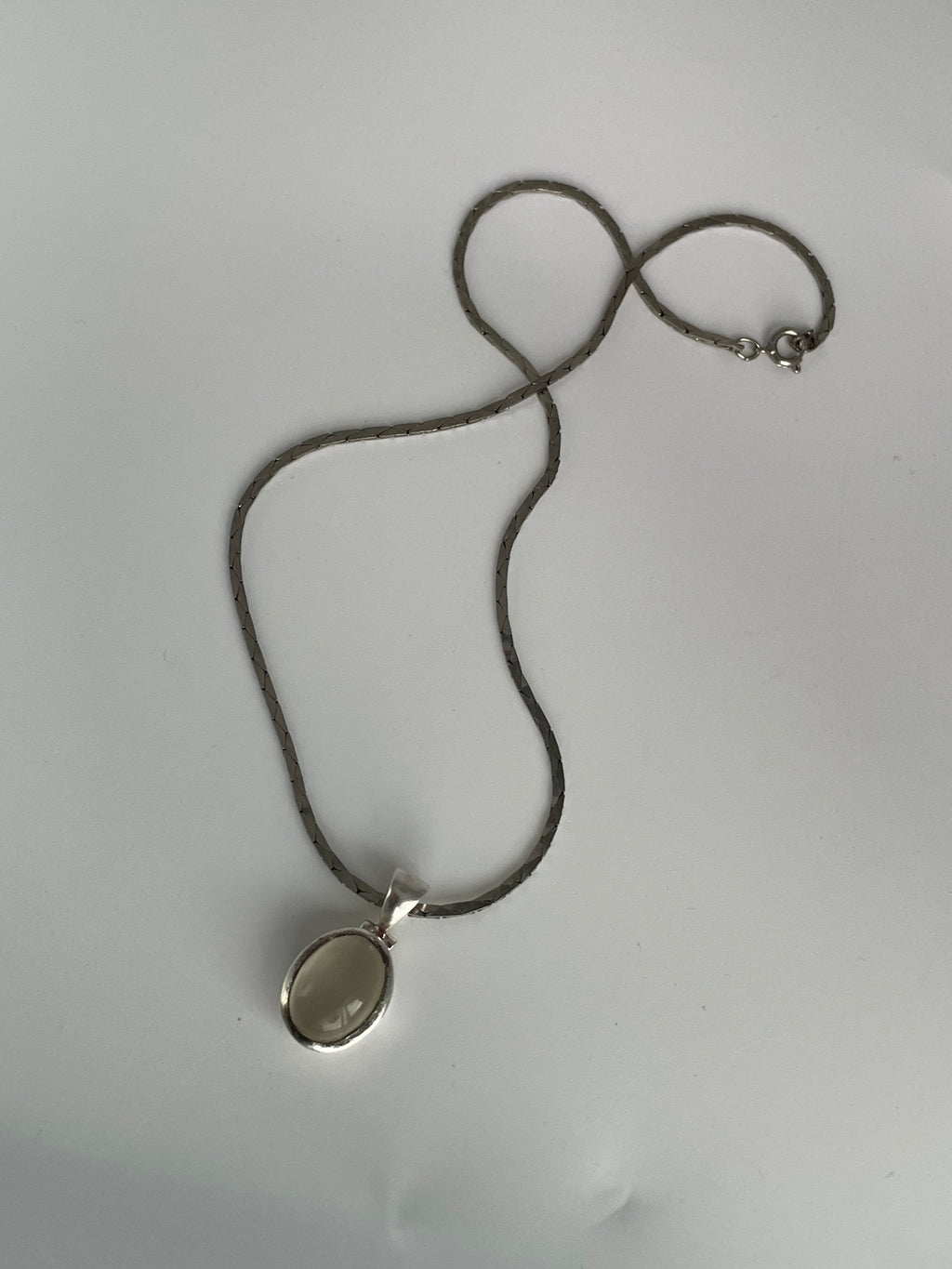 Cat's eye pendant with the optional flat link chain and spring ring clasp laid flat