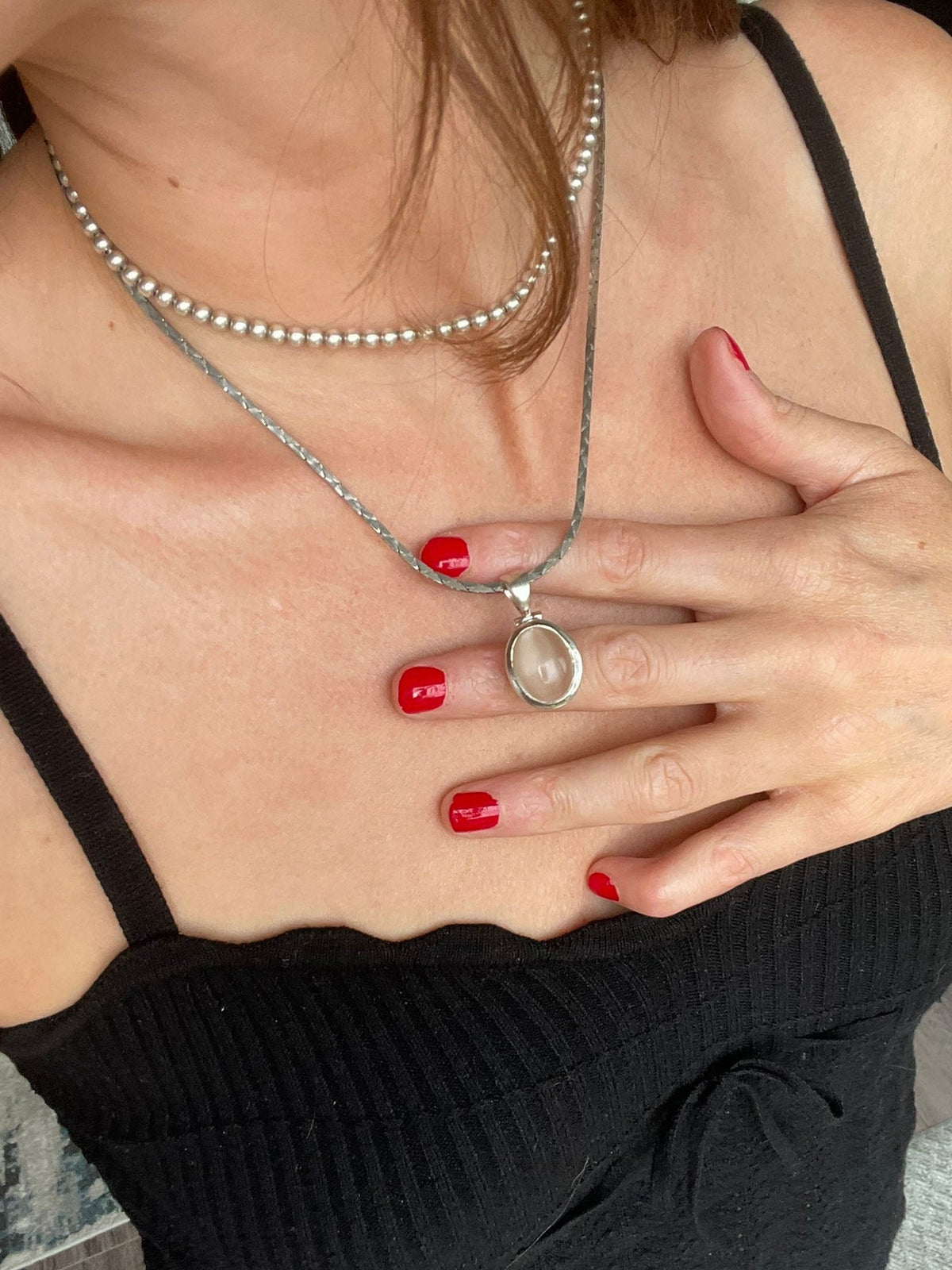 Cat's eye pendant worn on its flat link chain, styled with a beaded silver choker