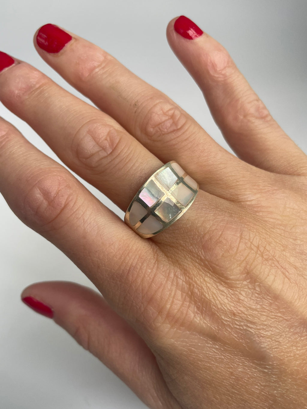 Silver dome ring inlaid with a grid of pink mother of pearl tiles, worn on the hand