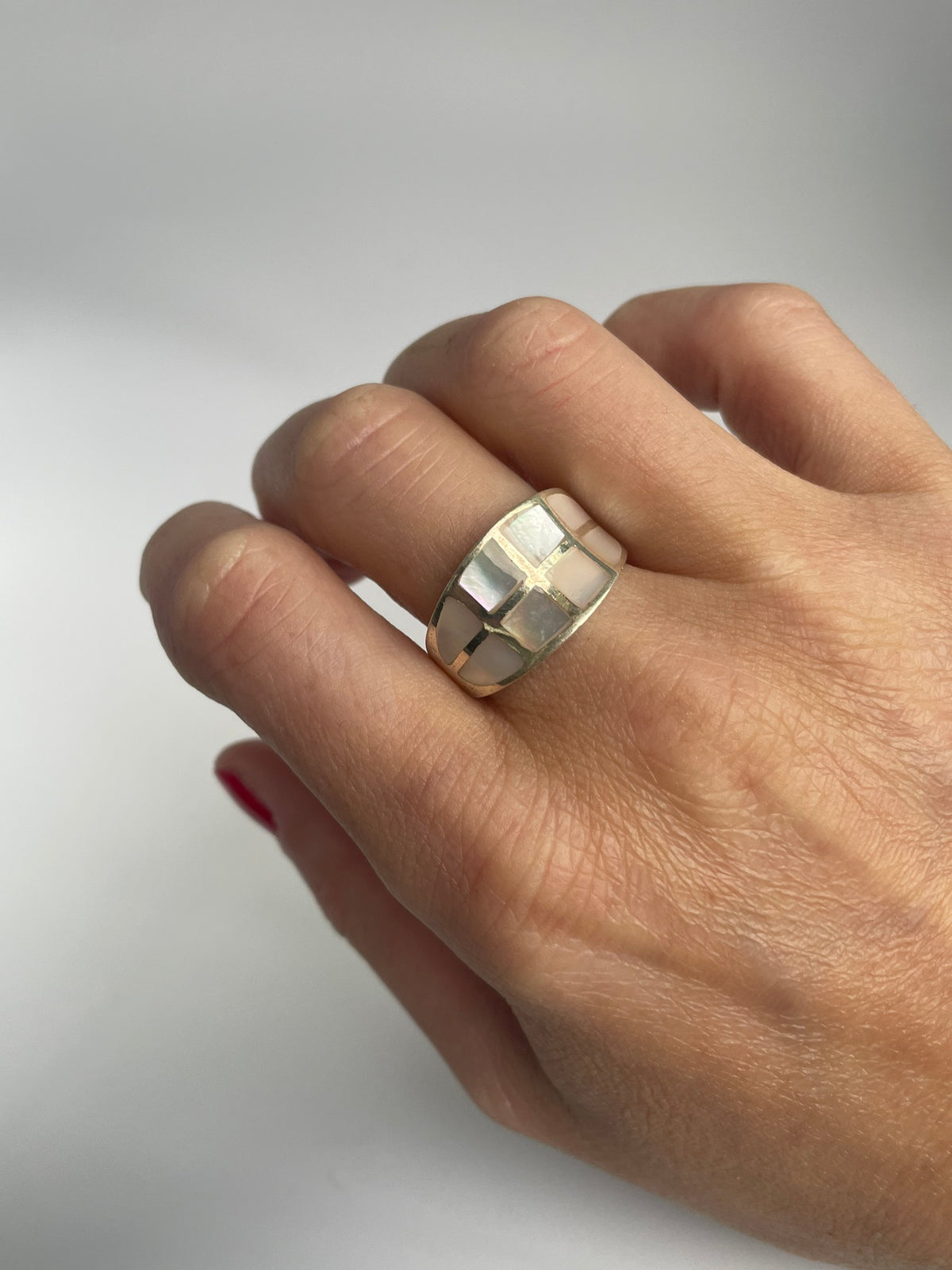 Pink mother of pearl mosaic ring on the finger, angled view of the tapered band