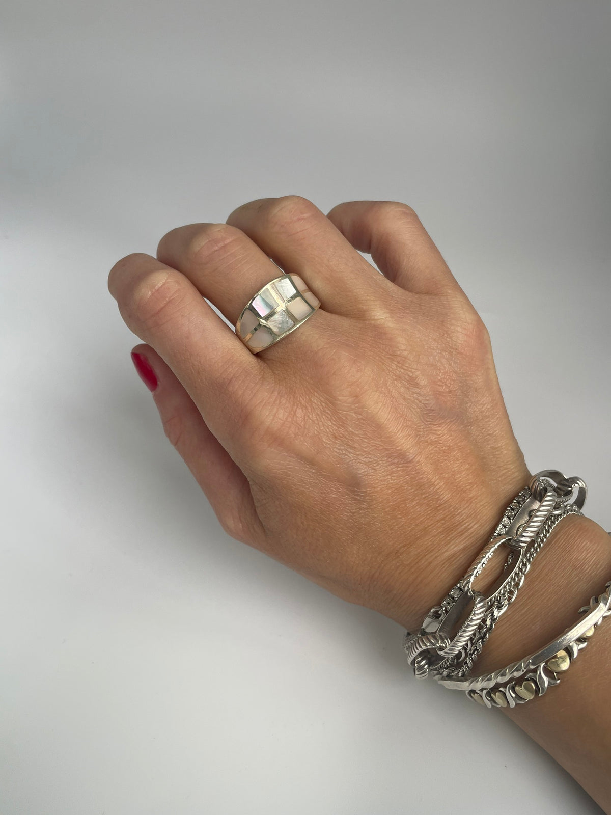 Pink mosaic dome ring on the hand, styled with silver bracelets