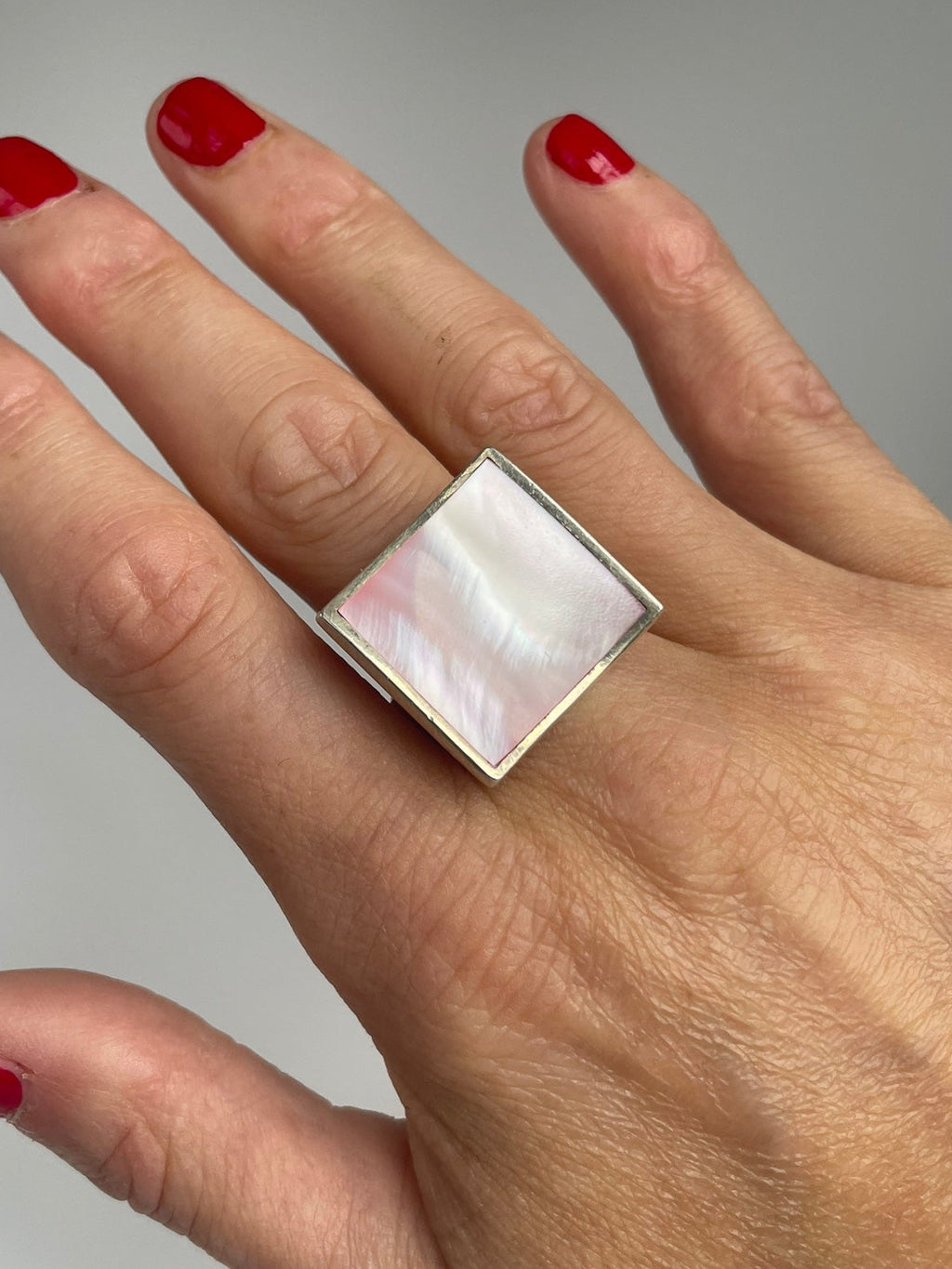 Large square pink mother of pearl ring set on point like a diamond, worn on the hand