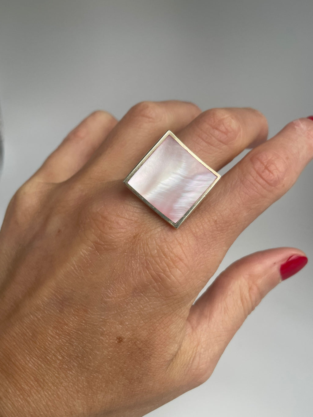 Pink mother of pearl square ring showing its rippled iridescent sheen