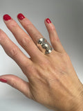 Wavy domed silver ring worn on the middle finger, showing its hourglass outline