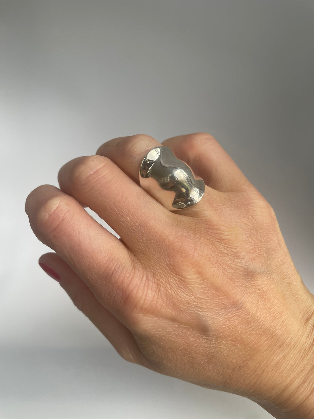 Chunky mirror polished silver saddle ring on the hand