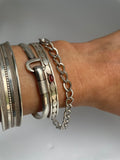 Silver curb chain bracelet worn next to cuffs and bangles for styling